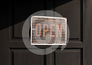 Sign with message Welcome OPEN on black wooden door