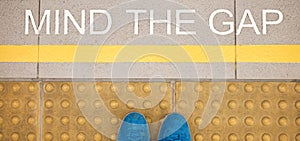 The sign Mind the gap painted on train station's platform edge