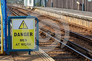 A sign next to train tracks reading Danger men at work