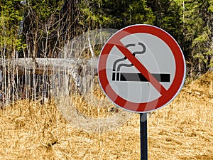 Sign no smoking on the background of forest and dry grass and trees.