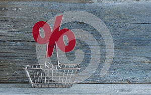sign percent and shopping cart on wood background
