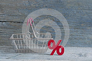 sign percent and shopping cart on wood background