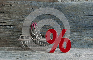 sign percent and shopping cart on wood background