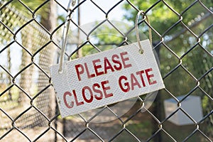 Sign with Please Close Gate hanged with a rope on a chain link fence- Navarre, Florida