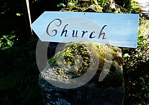 Sign pointing towards a church mossy wall