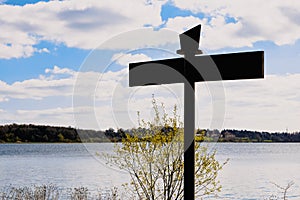 Sign post pointing out directions over a lake and landscape background