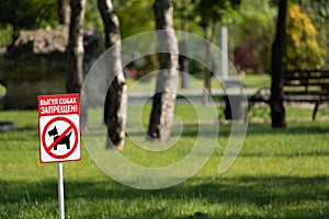 Sign prohibiting dog walking in a park, dont walk with dog on green lawn in park. Dog walking prohibited. Inscription on sign on