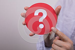 Sign of the question mark made of red paper in the hands of a man