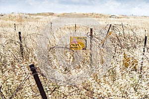 A sign reading `Danger Mines!` hangs from a barbed wire fence in the Golan Heights, near the border with Syria, Israel