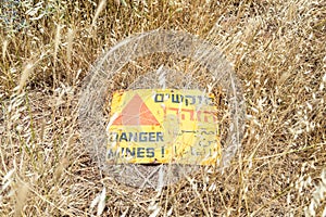 A sign reading `Danger Mines!` lies on the ground in the grass in the Golan Heights, near the border with Syria, Israel