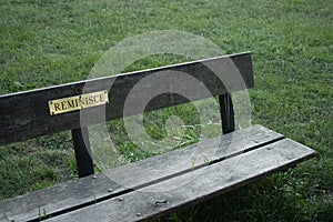 A sign reading `reminisce` on a park bench