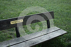 A sign reading `reminisce` on a park bench photo
