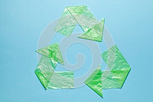 Sign recycling plastic from green bags on blue background. Environmental pollution by disposable bags, recycling