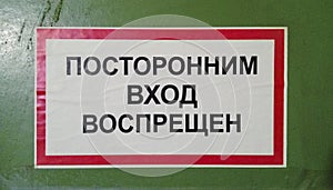 A sign in a red frame with a green background with the inscription of an outsider`s entrance is forbidden in Russian language