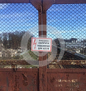 A sign on a rusty gate