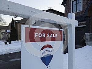 Sign for sale in front of a detached house in residential area.