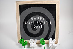 A Sign That Says Happy Saint Patty`s Day With Glitter Clovers and Gold Coins Around