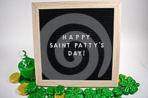 A Sign That Says Happy Saint Patty`s Day With Glitter Clovers and Gold Coins Around