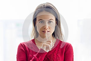 Sign secret, young woman showing silence sign with her finger on lips.