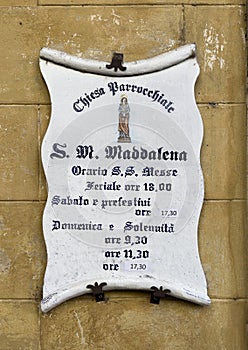 Sign with service times for the Church of Santa Maria Maddalena in the historic center of Castiglione del Lago, Italy. photo