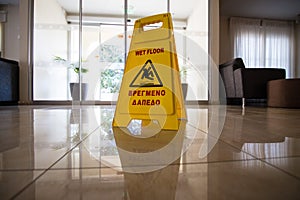 Sign showing warning of caution wet floor on wet tile floor in sunset