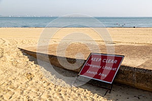 a sign at the side of a slipway on a beach with a sign saying keep clear emergency lifeboat launch area