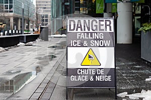 Sign on the sidewalk warning of the danger of ice and snow falling from the above
