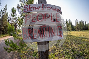 Sign - Slow Down People Breathing along a dirt word to prevent motorists from kicking up dust with cars