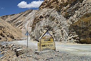 Sign SMILE PLEASE nearby mountain road in Ladakh