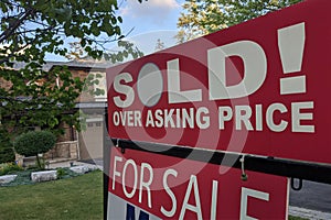 Sign sold over asking price for sale in front of detached house in residential area