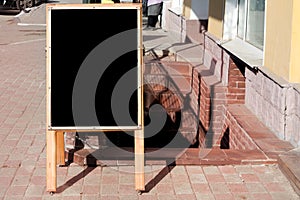 Sign stands at the entrance to the cafe on pavement, empty, space for text