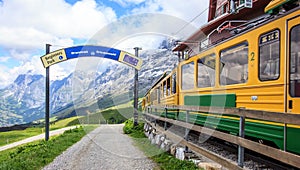 Sign of Starting point to begin walking trail with view of Swiss wengernalpbahn railways train departing Kleine Scheidegg station