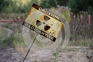 A sign stuck in the ground with the words: caution, radiation, at an angle. Warning sign in an infected area of radioactive danger