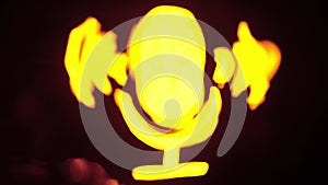 Sign template isolated on black background. Neon yellow microphone symbol glowing with water waves moving over icon with