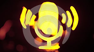 Sign template isolated on black background. Neon yellow microphone symbol glowing with water waves moving over icon with