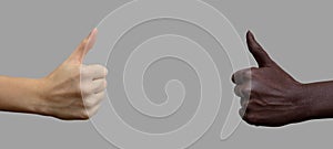 The sign of the thumb. Two hands with black and white skin, showing the like sign on a gray isolated background. Close-up,