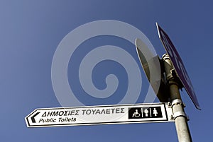 Sign to the public restrooms with text in Greek and English