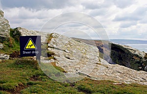 Sign at the top of a high coastal cliff, warning of the danger o