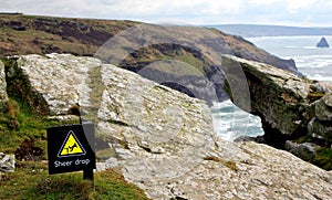 Sign at the top of a high coastal cliff, warning of the danger o