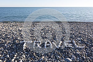 The sign Travel made from white pebbles on pebble beach on the s