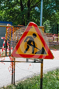 A sign under construction on a closed road. A warning sign under construction, a work-in-progress sign