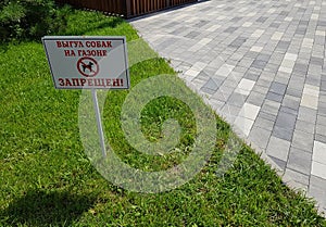 Sign Walking dogs is prohibited or walking with a dog is prohibited on the background of green grass. Beautiful horizontal photo