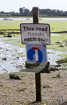 A sign warning against car parking on a road that floods with each high tide