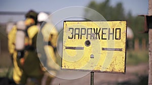 A sign warning of danger. Clip. People performing work in a dangerous area going to a gas mask on the background of a