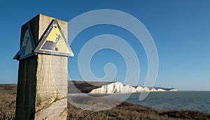 Sign warning of the danger of erosion at the cliff edge overlooking Seven Sisters at Seaford in East Sussex, south coast of UK