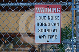 Sign warning loud noise horns can sound at any time on the fence at port.