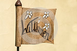 Sign `Welcome` in flag form made of clay with flowers