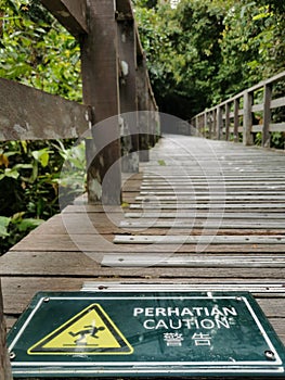 Sign on the wooden bridge showing warning of caution wet floor.