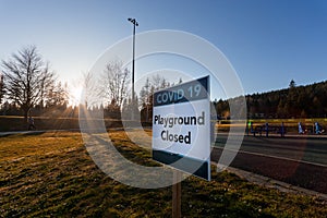 A sign and yellow caution tape indicating that the playground is closed due to the Covid 19 pandemic