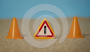 Signal of attention together with cones of work on sand of beach and blue sky bottom and with spaces around the motive to be able